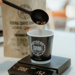 Coffee beans being carefully measured into a cup using a digital scale, focusing on precise brewing.