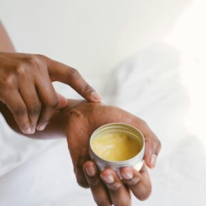 Close-up of a hand applying natural skincare cream, emphasizing self-care and holistic health.